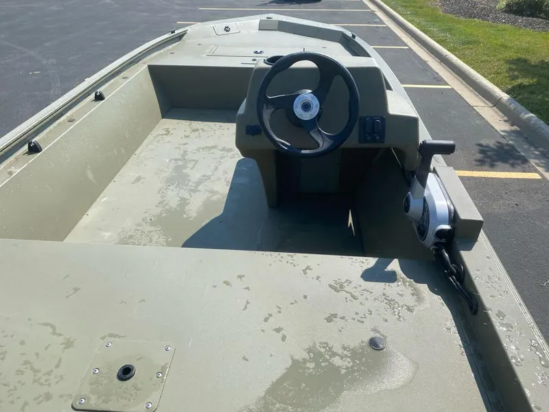 Slide: The Image of 2024 Tracker Grizzly 1648 SC boat interior with steering wheel, parked outdoors. - 5