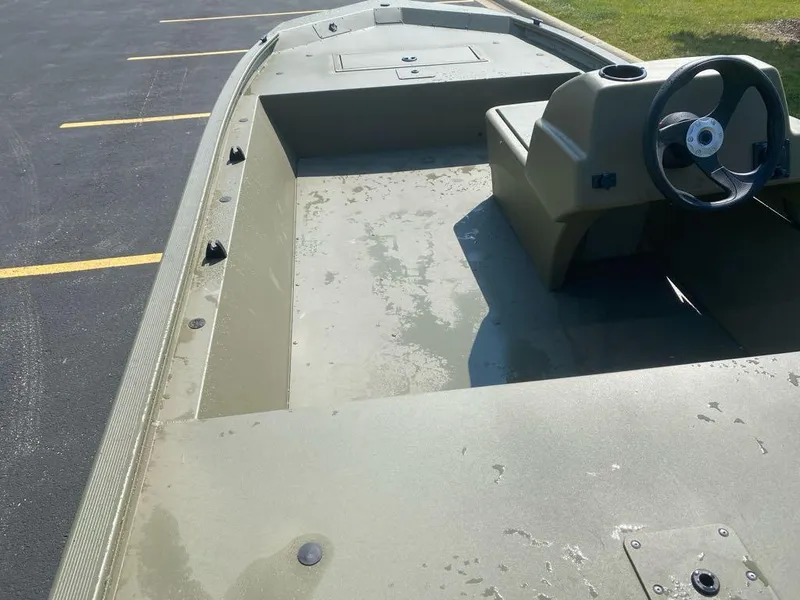 Slide: The Image of 2024 Tracker Grizzly 1648 SC boat interior with steering console, parked on asphalt. - 6