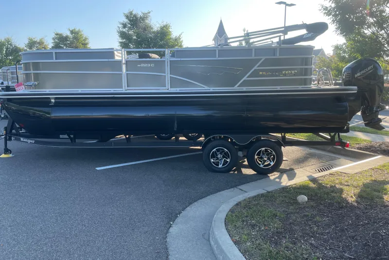 The Image of 2024 Ranger Reata 223C pontoon boat on trailer in parking lot. - 0