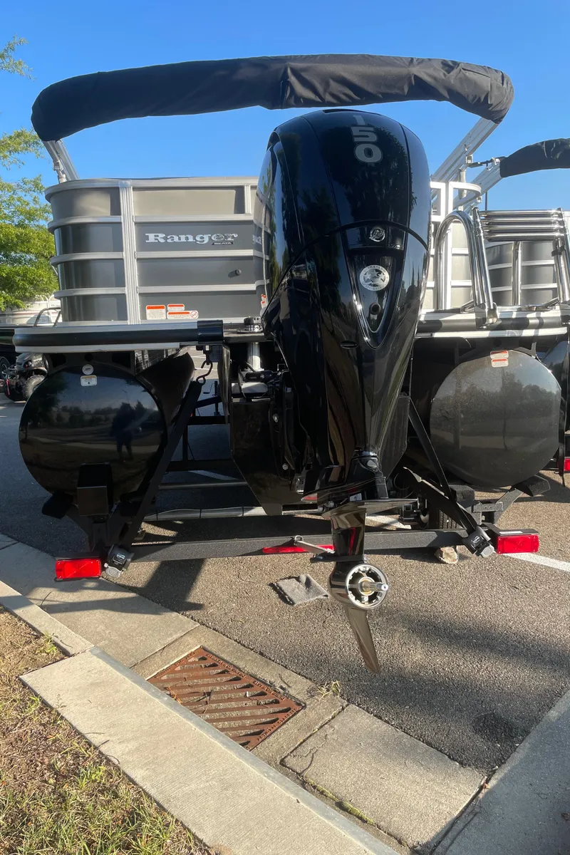 Slide: The Image of 2024 Ranger Reata 223C boat with powerful outboard motor, parked on a sunny day. - 6