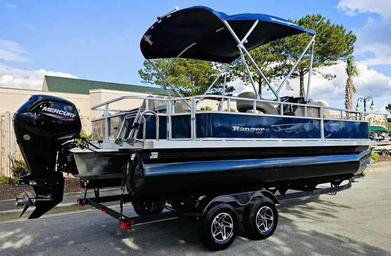 Slide: The Image of 2024 Ranger Reata 200F pontoon boat with Mercury outboard motor, parked on trailer. - 1