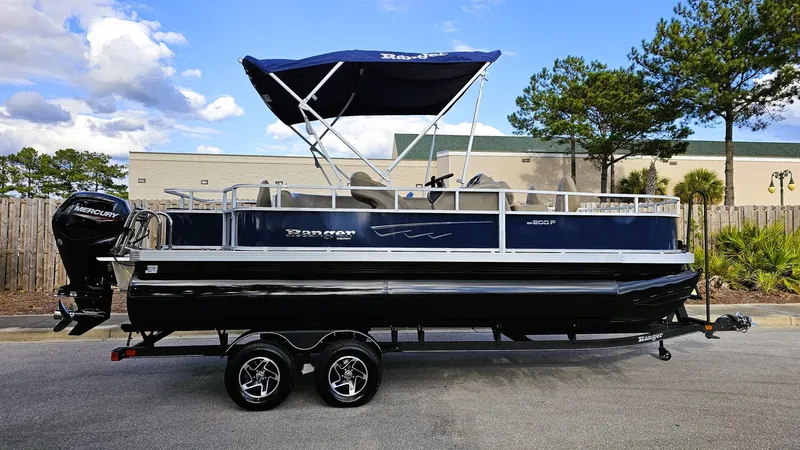 Slide: The Image of 2024 Ranger Reata 200F pontoon boat with canopy, parked on a trailer. - 9