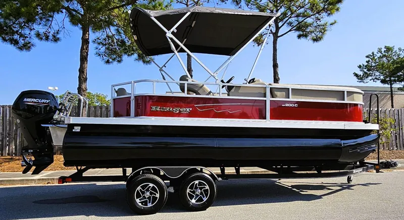 The Image of 2024 Ranger Reata 200C pontoon boat on trailer, parked outdoors. - 0
