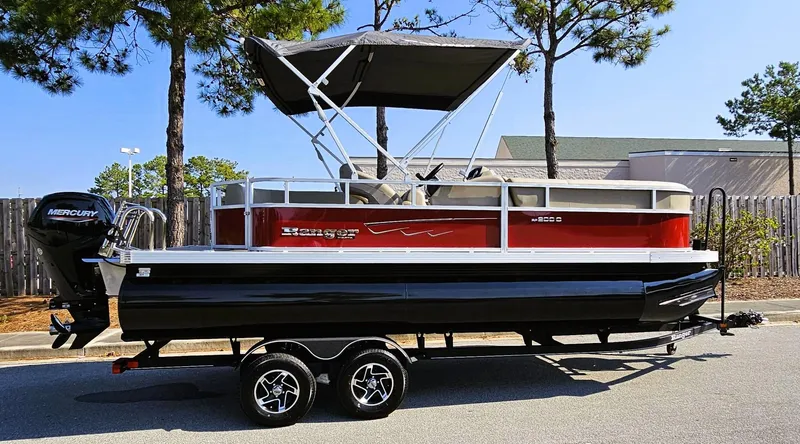 Slide: The Image of 2024 Ranger Reata 200C pontoon boat on trailer, red and black design, parked outdoors. - 3
