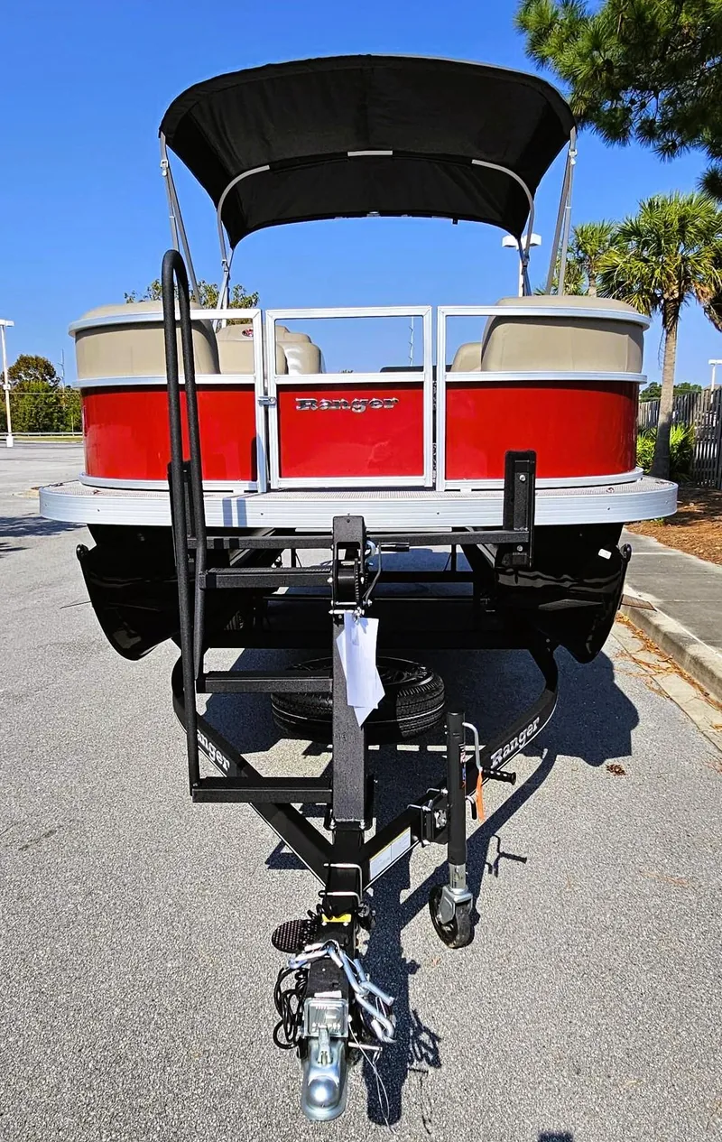 Slide: The Image of 2024 Ranger Reata 200C pontoon boat on trailer, red and white design, parked outdoors. - 7