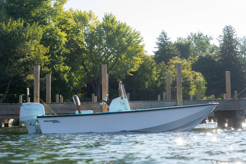 Slide: The Image of 2024 Wolfeboro Classic 15 boat docked on a serene lake with lush trees. - 5