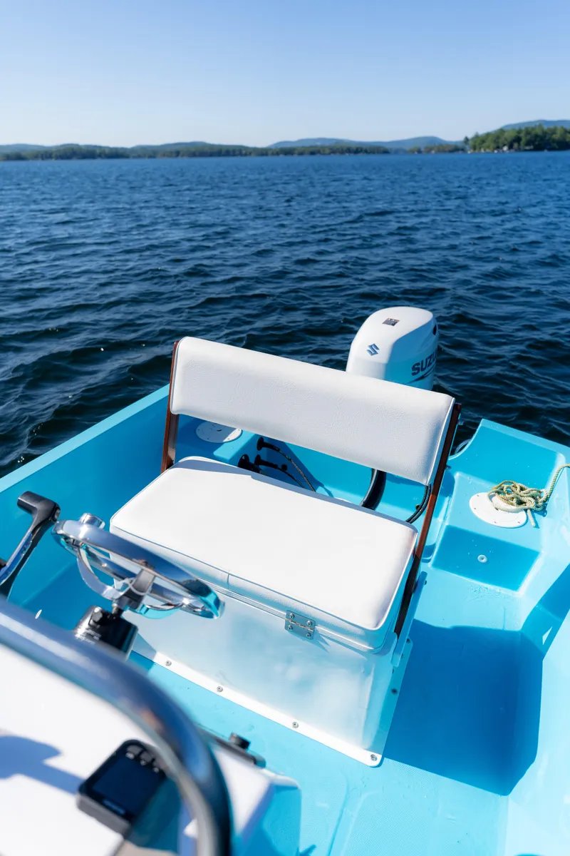 Slide: The Image of 2024 Wolfeboro Classic 15 boat on a lake, featuring a white seat and blue interior. - 9
