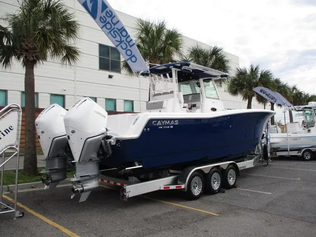 Slide: The Image of 2024 Caymas 30CAT boat on trailer, displayed outdoors with palm trees. - 1
