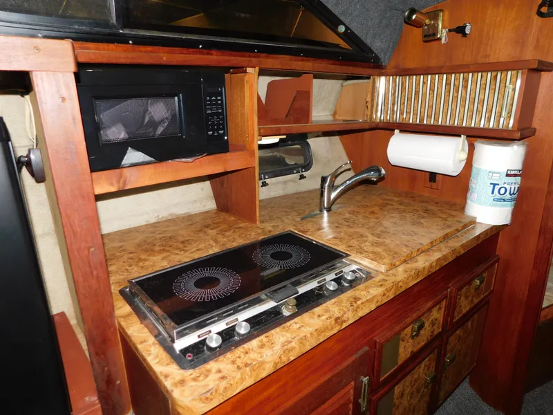 Slide: The Image of 1984 Cruisers International 296 Avanti Vee boat kitchen with stove, microwave, and sink. - 7