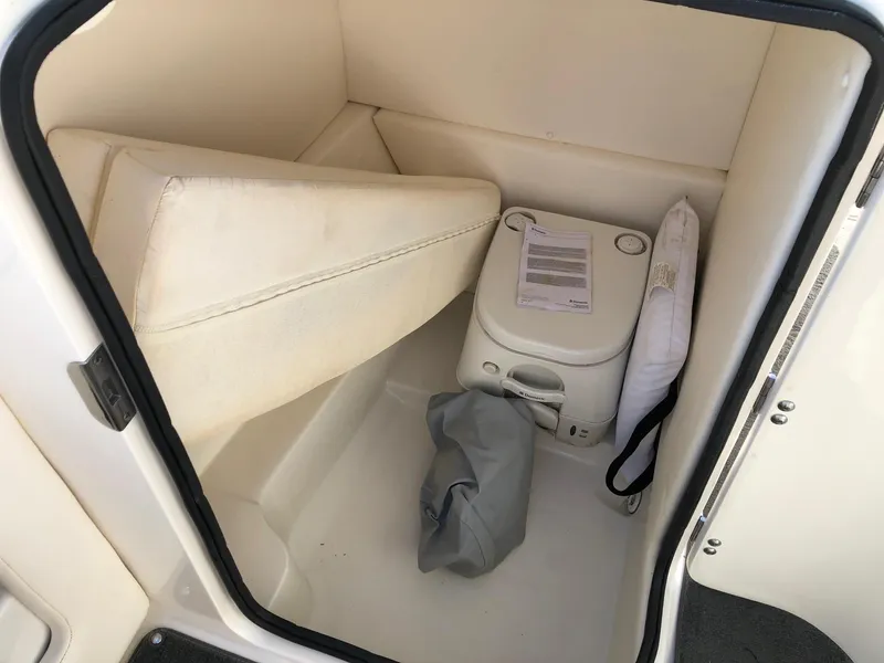 Slide: The Image of 2012 Sea Ray 240 Sundeck interior storage with portable toilet and cushion. - 10