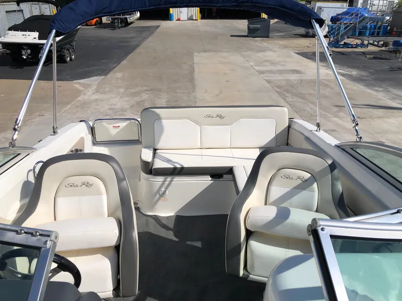 Slide: The Image of 2012 Sea Ray 240 Sundeck interior with white seating and blue canopy. - 12
