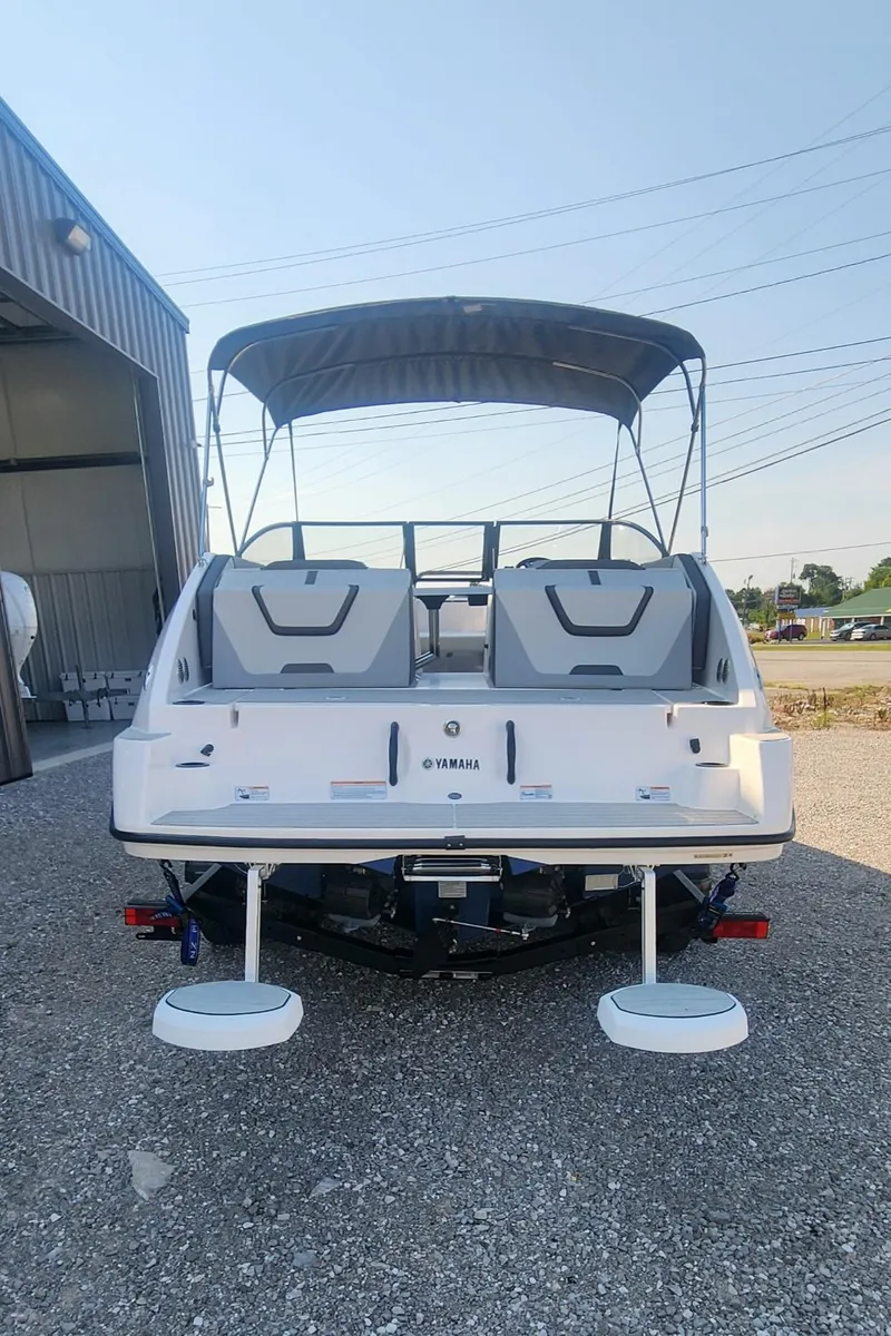 Slide: The Image of 2023 Yamaha Boats SX220 with canopy, rear view in outdoor setting. - 2