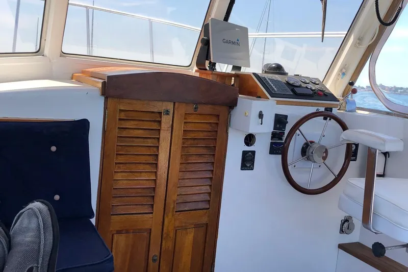 Slide: The Image of 1987 Harris Cuttyhunk Down East boat interior with wooden cabinetry and steering wheel. - 13
