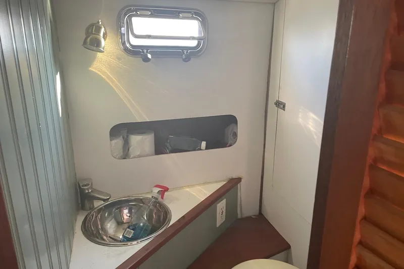 Slide: The Image of 1987 Harris Cuttyhunk Down East boat bathroom with sink, window, and storage shelf. - 2