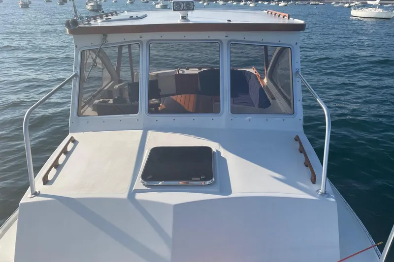 Slide: The Image of 1987 Harris Cuttyhunk Down East boat on water, front view with clear windows and calm sea. - 20