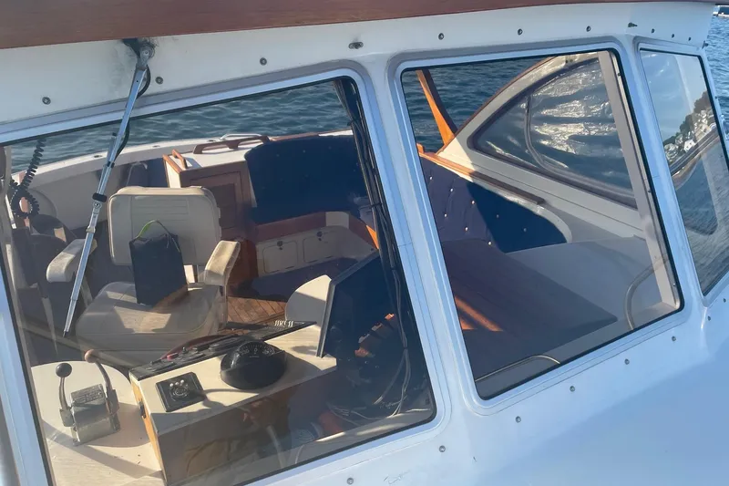 Slide: The Image of 1987 Harris Cuttyhunk Down East boat interior with steering wheel and seating, viewed through windows. - 21