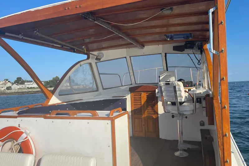 Slide: The Image of 1987 Harris Cuttyhunk Down East boat interior with wooden accents, docked on calm water. - 24