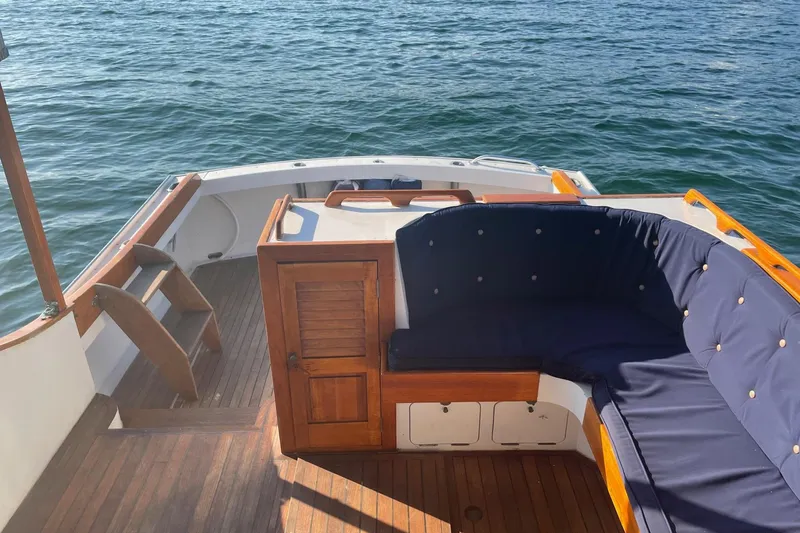 Slide: The Image of 1987 Harris Cuttyhunk Down East boat with wooden deck and cushioned seating on the water. - 27