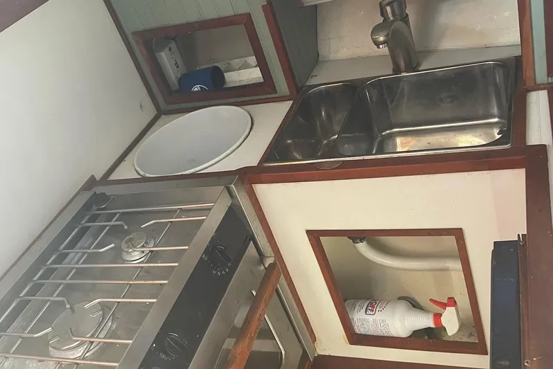 Slide: The Image of Compact kitchen area in a 1987 Harris Cuttyhunk Down East boat, featuring a stove and sink. - 6