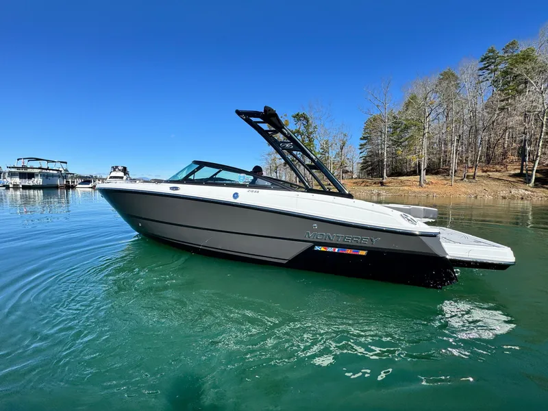 Slide: The Image of 2024 Monterey 218SS boat on a serene lake with clear blue skies. - 2