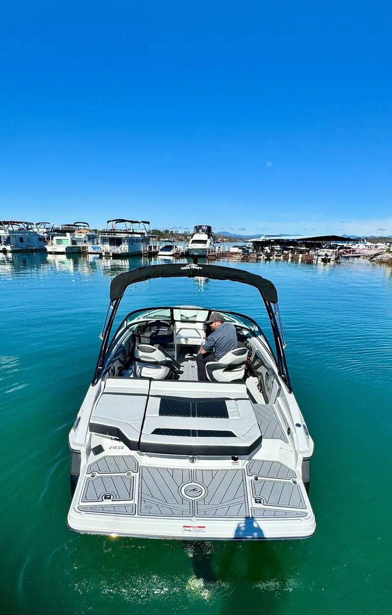 Slide: The Image of 2024 Monterey 218SS boat on calm water, marina in background. - 5