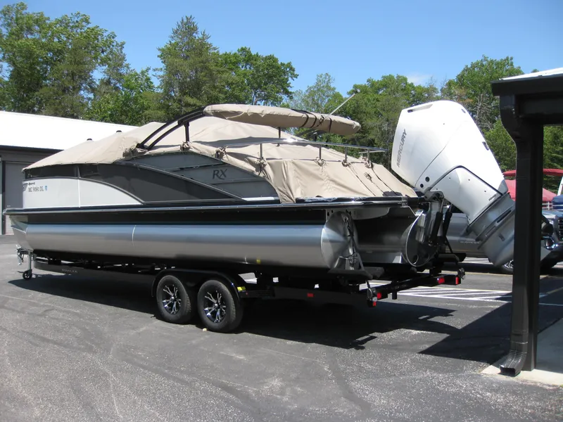 Slide: The Image of 2024 Bennington 25RX Swingback Windshield pontoon boat on trailer, covered, with outboard motor. - 2