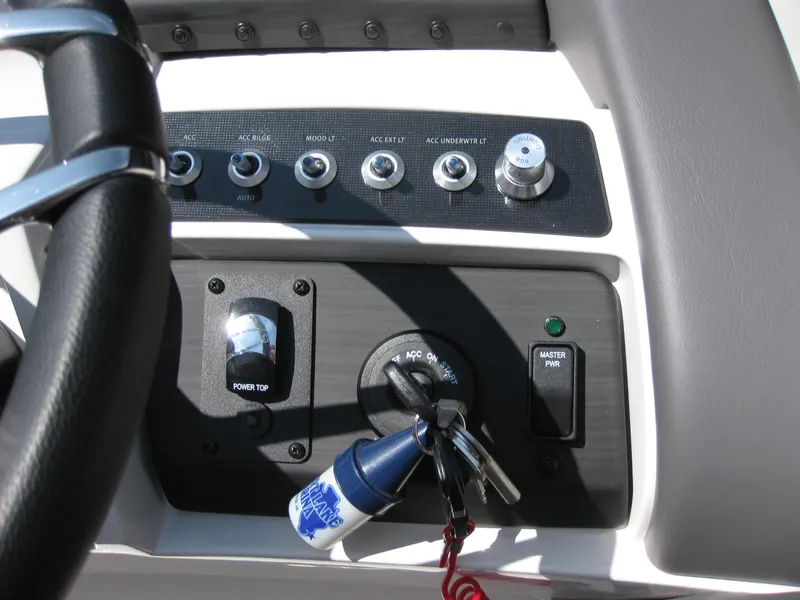 Slide: The Image of 2024 Bennington 25RX Swingback Windshield dashboard with controls and ignition keys. - 22