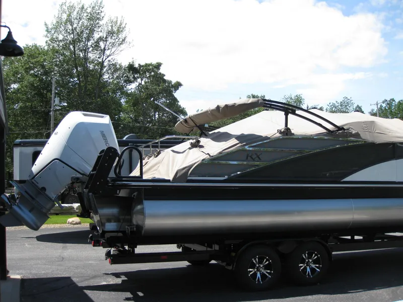 Slide: The Image of 2024 Bennington 25RX Swingback Windshield boat on trailer, covered and parked outdoors. - 4