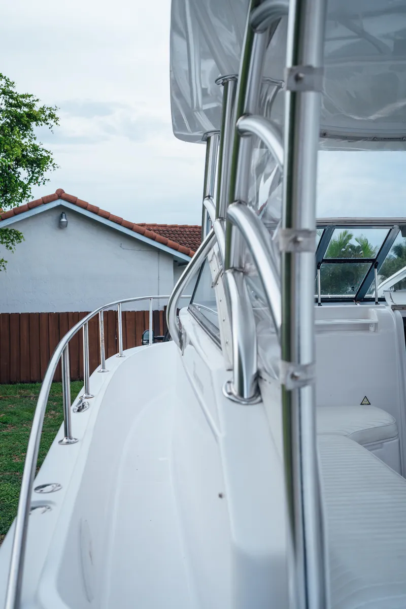 Slide: The Image of 2003 Pro-Line 32 Express boat with sleek railing and seating, docked near a house. - 8