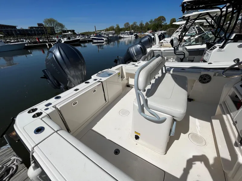 Slide: The Image of 2021 Cobia 240 Center Console boat docked, featuring spacious seating and dual outboard motors. - 4