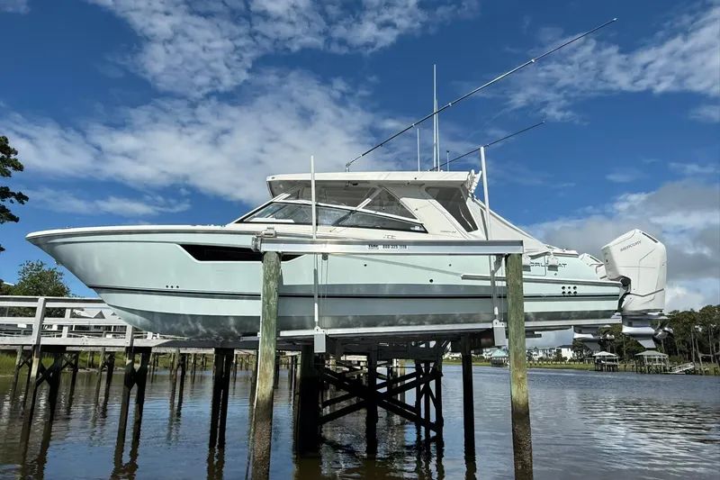 Slide: The Image of 2023 World Cat 400 DC-X boat on lift, clear sky background. - 3