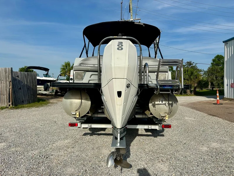 Slide: The Image of 2021 Harris Grand Mariner 250 pontoon boat with powerful outboard motor, parked on gravel. - 4