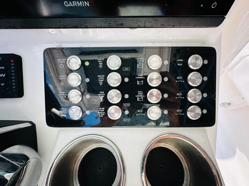 Slide: The Image of Control panel of 2024 Caymas 281 HB boat with various switches and cup holders. - 19