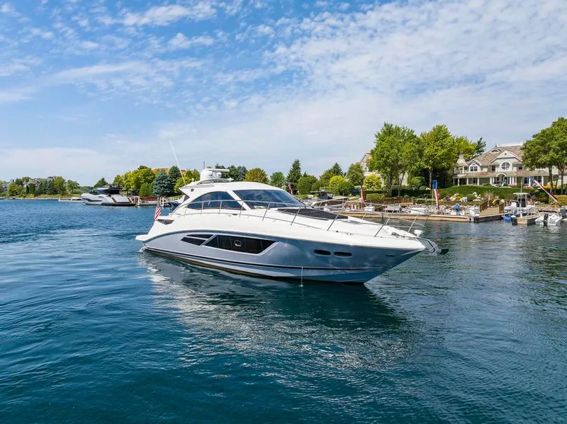 Slide: The Image of 2015 Sea Ray 510 Sundancer yacht cruising on a serene lake near a marina. - 5