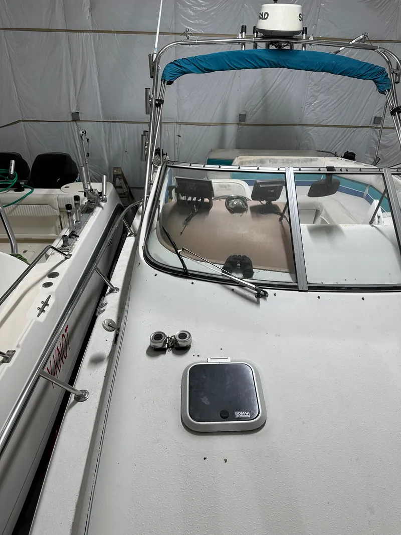 Slide: The Image of 1993 Rinker 280 Fiesta Vee boat in storage, featuring a blue canopy and windshield. - 12
