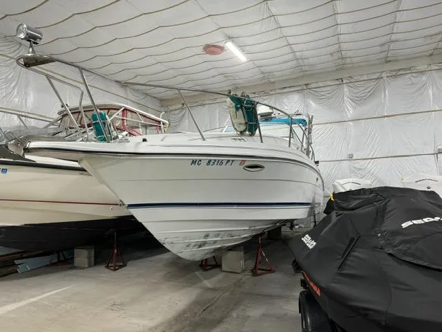 Slide: The Image of 1993 Rinker 280 Fiesta Vee boat stored indoors, alongside covered jet skis. - 2