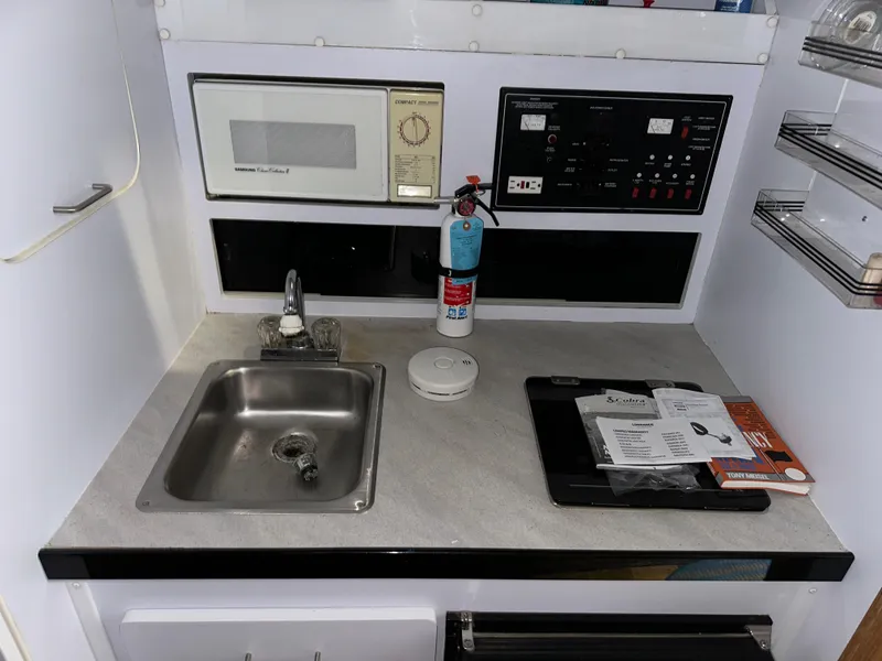 Slide: The Image of 1993 Rinker 280 Fiesta Vee boat kitchenette with sink, microwave, and control panel. - 26