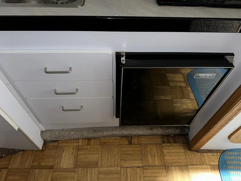 Slide: The Image of 1993 Rinker 280 Fiesta Vee interior with drawers and a compact fridge. - 27