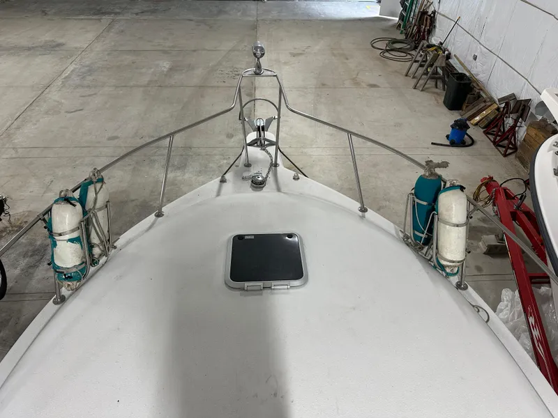 Slide: The Image of 1993 Rinker 280 Fiesta Vee boat bow in storage, featuring deck hatch and safety railings. - 7