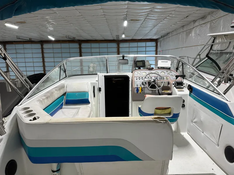 Slide: The Image of 1993 Rinker 280 Fiesta Vee boat interior with steering wheel and seating in a storage facility. - 8