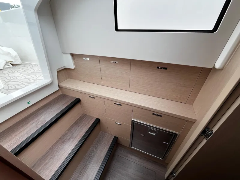 Slide: The Image of 2024 Jeanneau DB37 interior with wooden stairs, storage cabinets, and a window. - 20