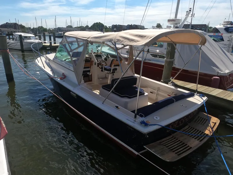 Slide: The Image of 2005 Hunt Yachts Surfhunter 25 docked at marina, featuring canopy and spacious deck. - 16