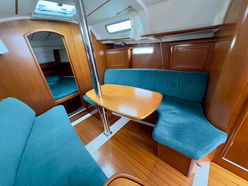 Slide: The Image of Interior of 2001 Beneteau Oceanis 331 sailboat with blue seating and wooden table. - 14