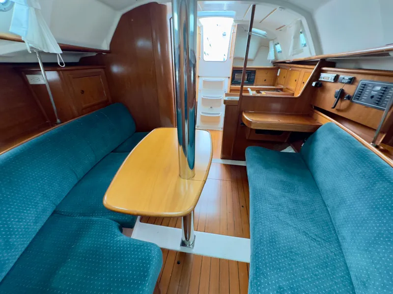 Slide: The Image of Interior of 2001 Beneteau Oceanis 331 sailboat with blue seating and wooden table. - 18