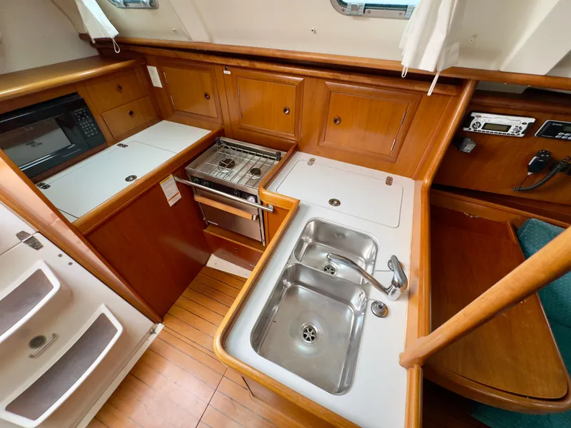 Slide: The Image of Galley kitchen in 2001 Beneteau Oceanis 331 sailboat with stove, sink, and wood cabinetry. - 9