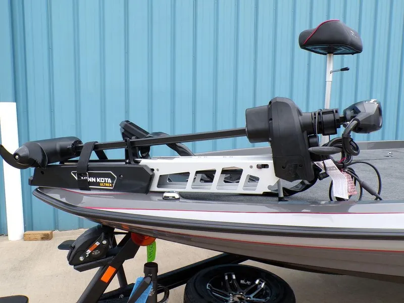 Slide: The Image of 2025 Skeeter ZXR21 boat with Minn Kota trolling motor, docked near blue wall. - 11