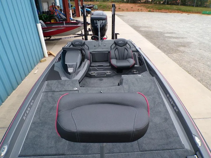 Slide: The Image of 2025 Skeeter ZXR21 boat interior with seating and motor, parked near a blue building. - 6