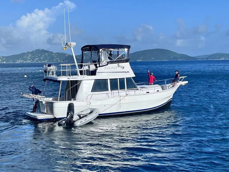 The Image of 1999 Mainship 350 Trawler on calm blue waters with distant green hills. - 0