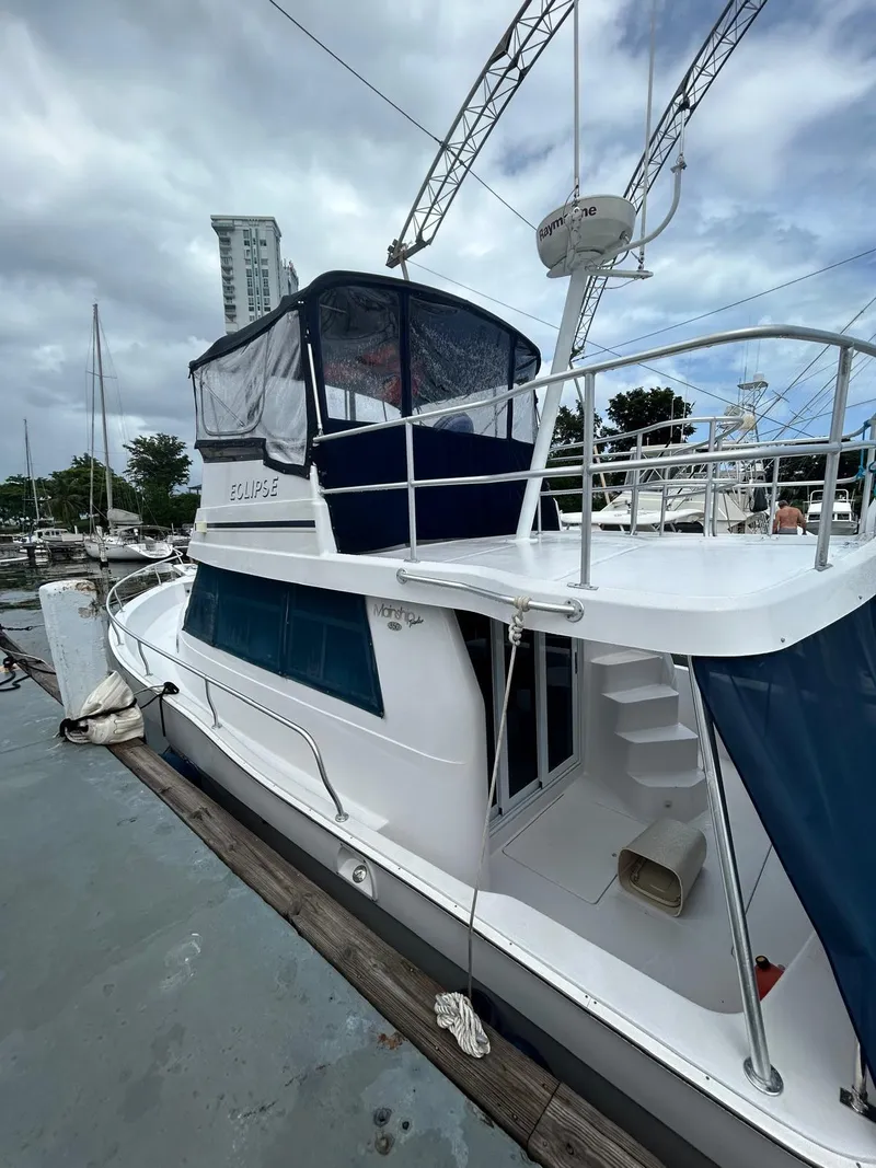 Slide: The Image of 1999 Mainship 350 Trawler docked at marina, featuring upper deck and enclosed cockpit. - 3