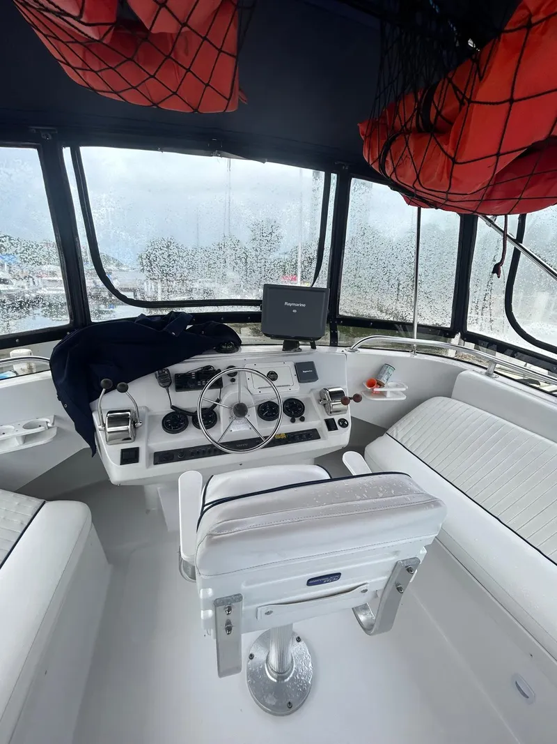 Slide: The Image of 1999 Mainship 350 Trawler helm with steering wheel, navigation equipment, and seating. - 4